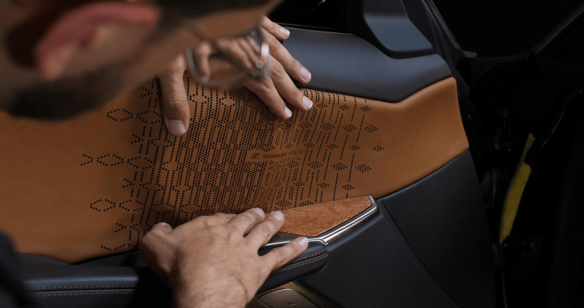 Man showing the Sennheiser Ambeo Sign on the inside of a car door