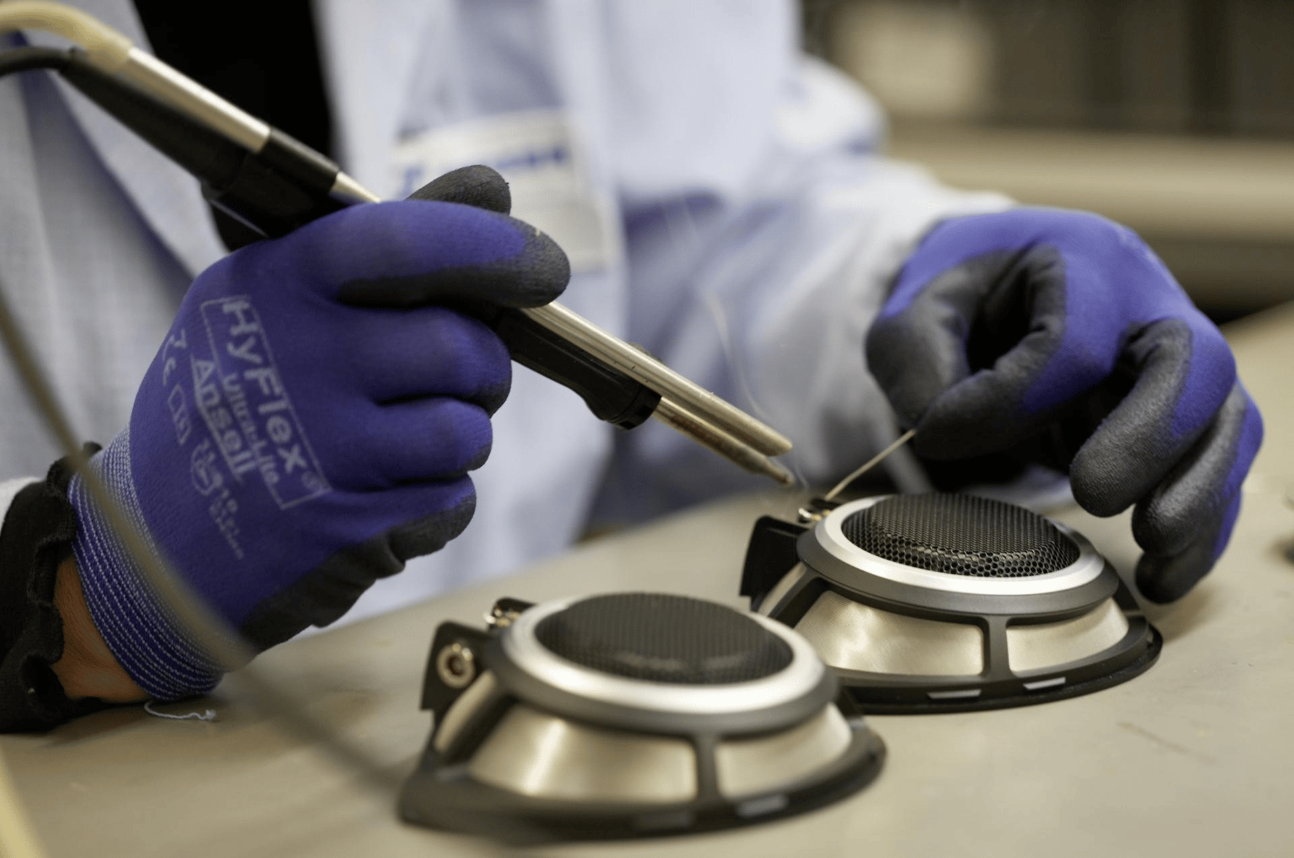 Person wearing protective gloves assembling speaker components