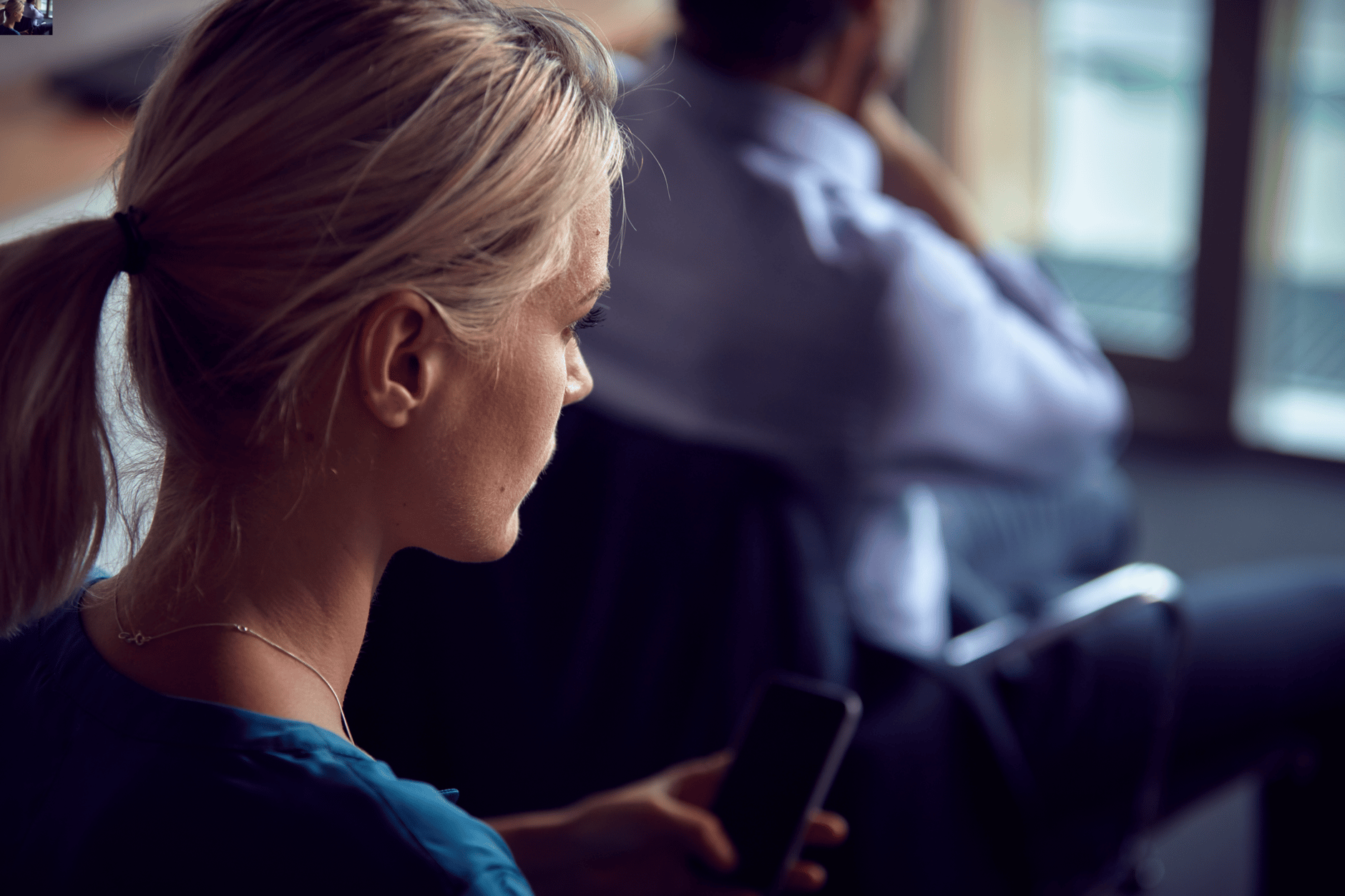 Woman sitting and looking at smartphone in office setting.