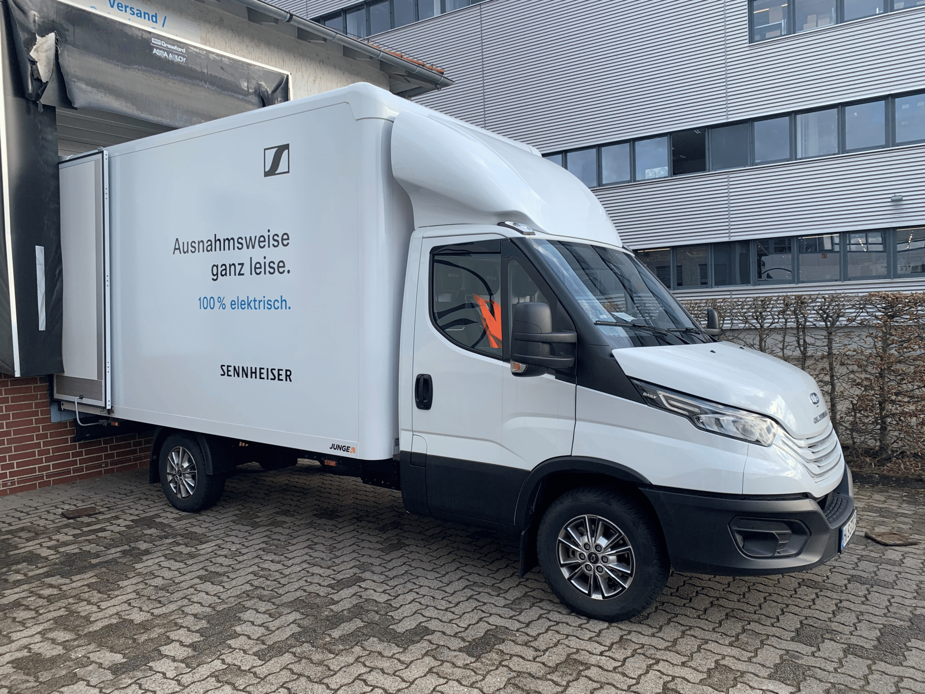 Sennheiser electric delivery truck parked outside production hall.