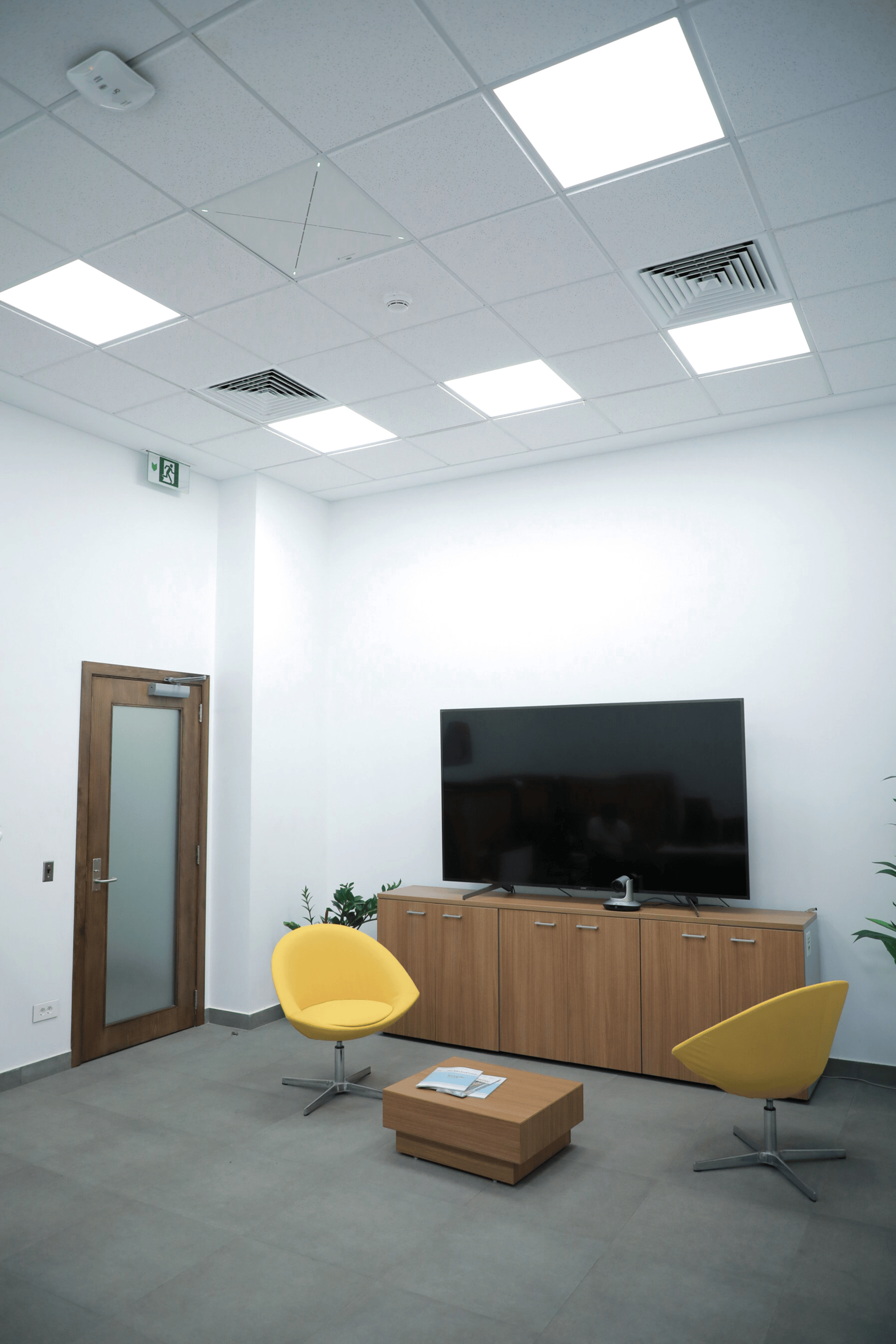 Modern meeting room with yellow chairs, large screen, and wooden cabinet at American University of Beirut.