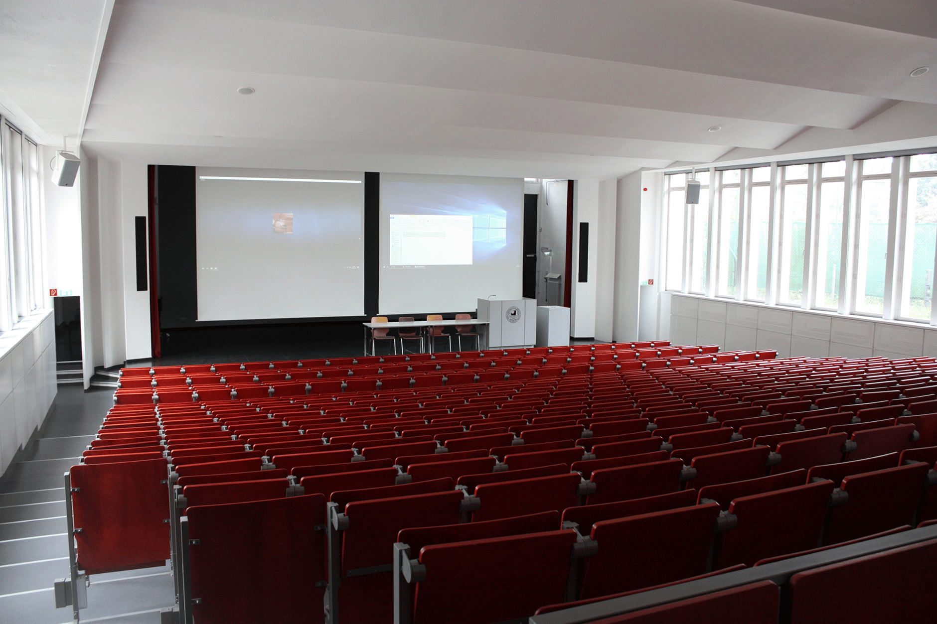 Lecture hall at Freie University Berlin with red seats and a presentation screen.