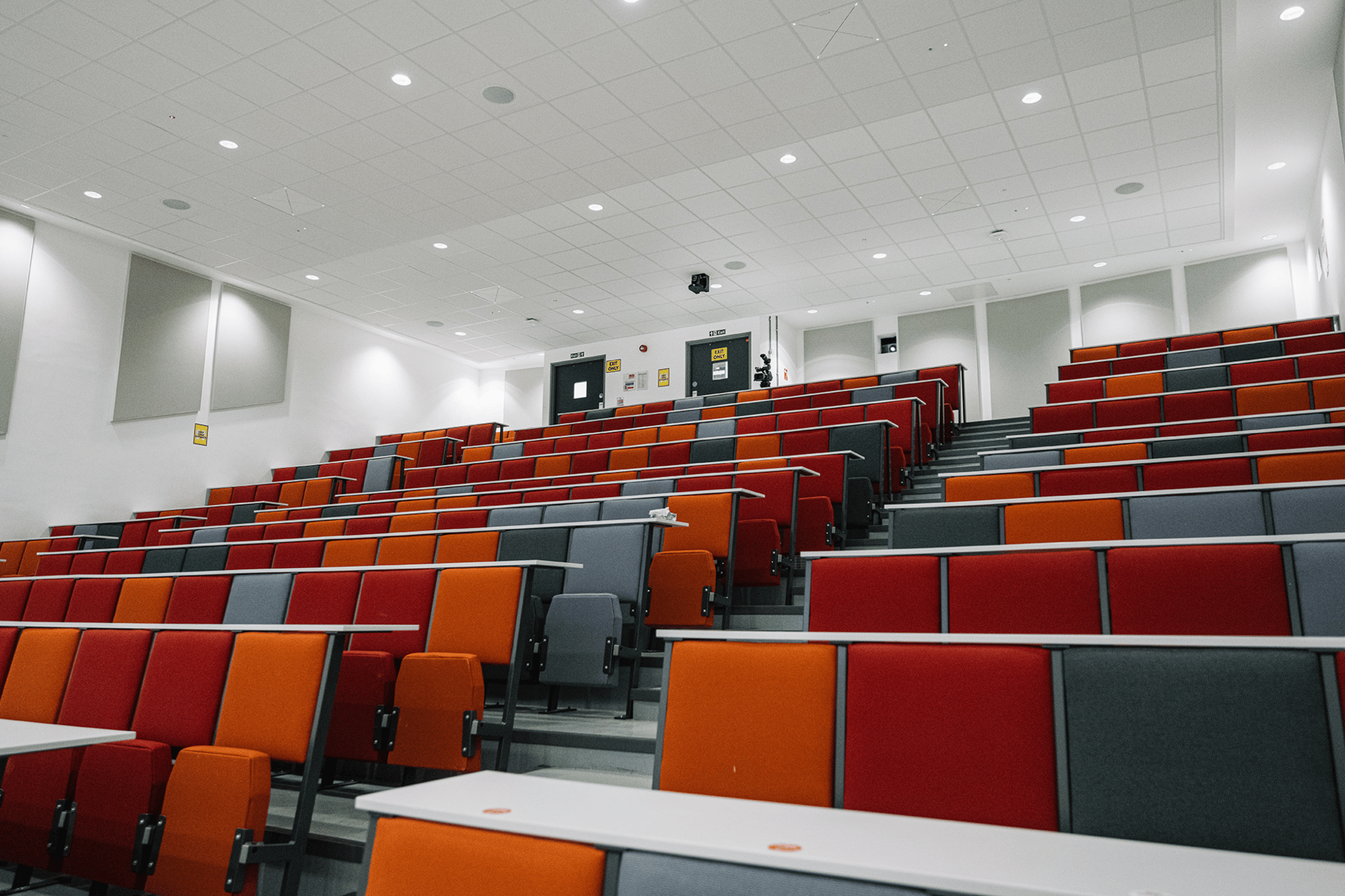 Modern lecture hall with red and orange seating at Queen's University Belfast.