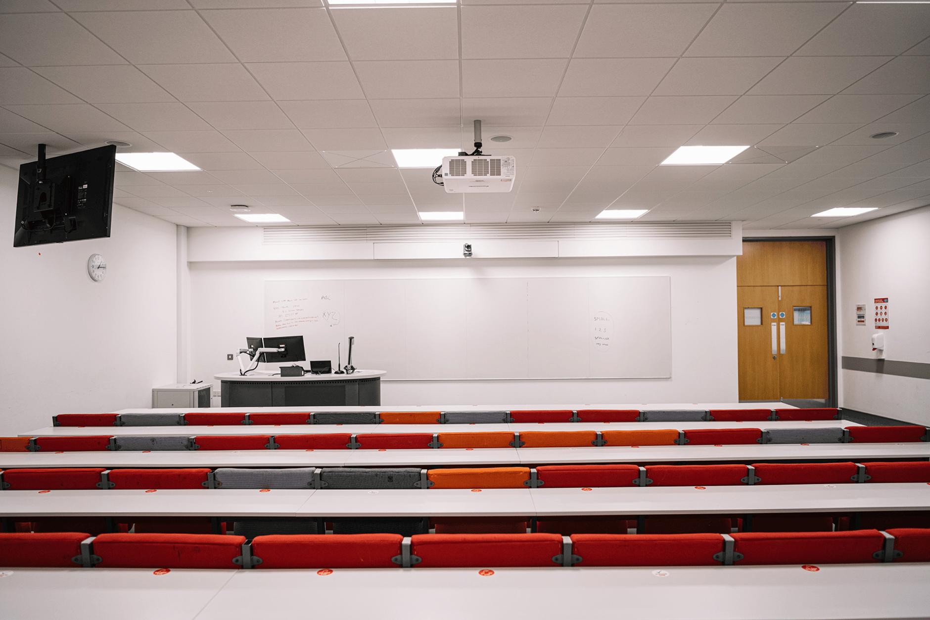 Lecture room at Queen's University Belfast with desks, chairs, and a ceiling-mounted projector.