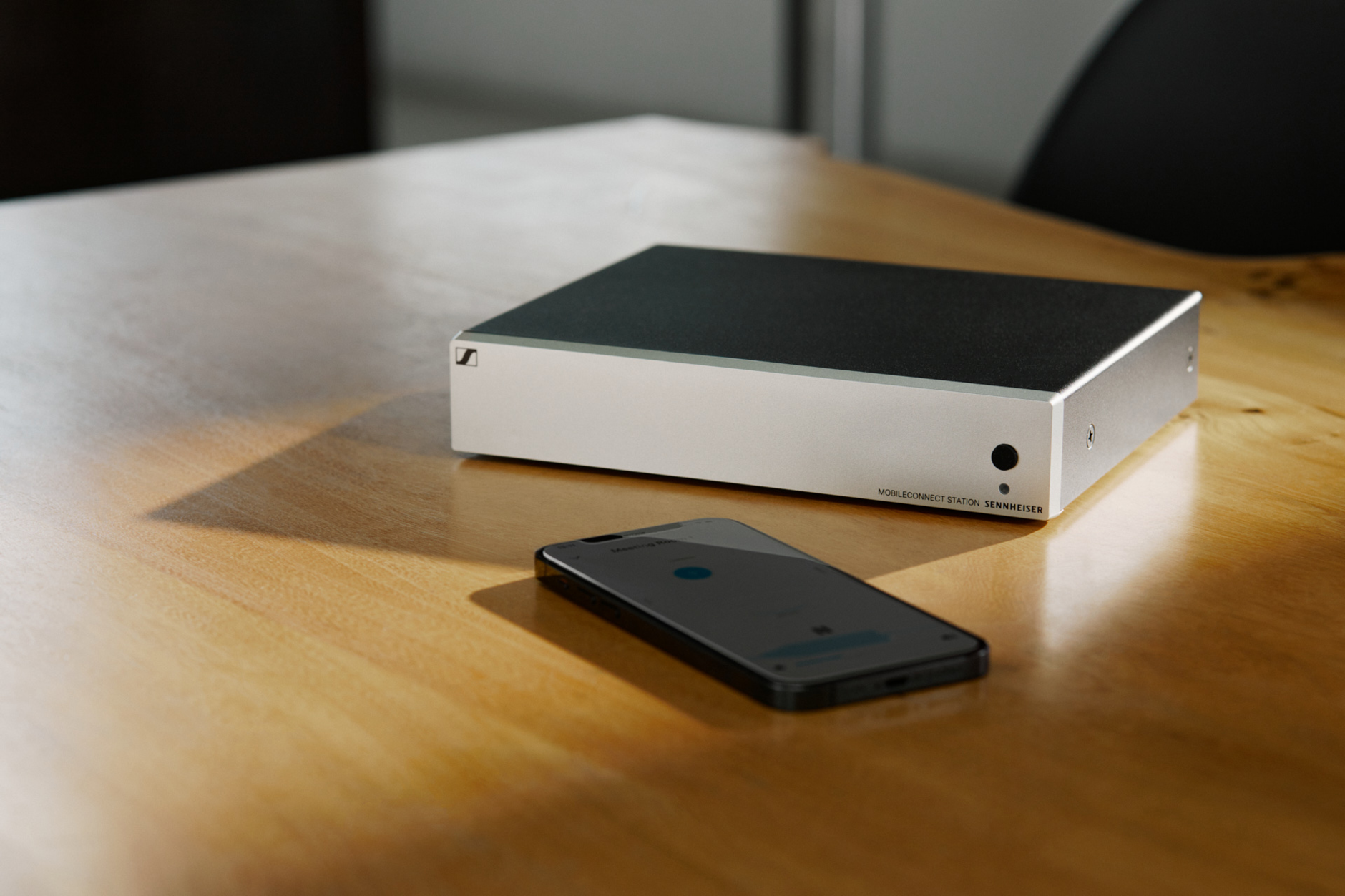 Sennheiser MobileConnect device on a wooden table next to a smartphone.