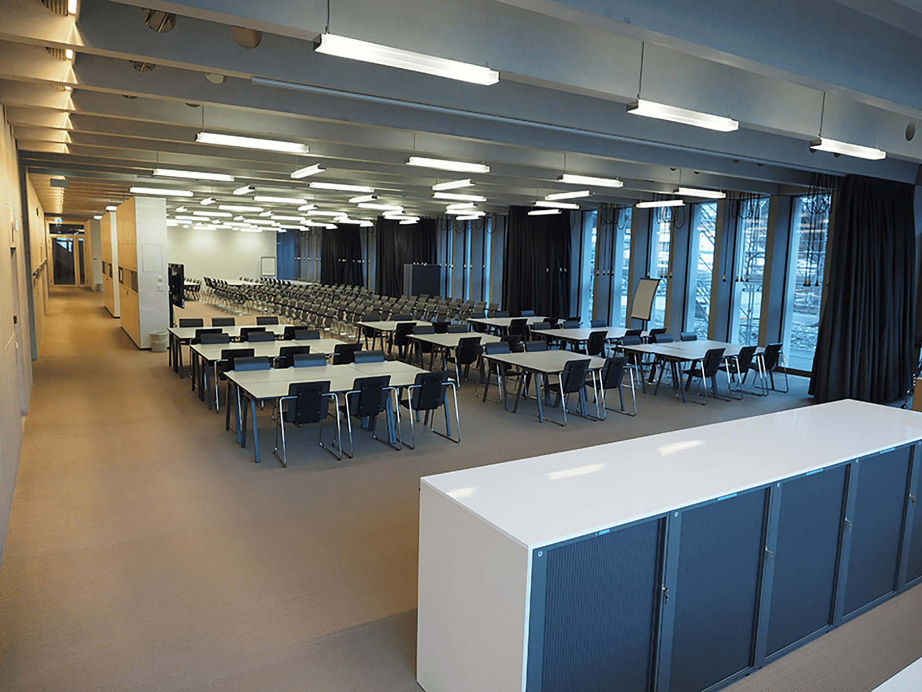 Large conference room with rows of tables and chairs at the University of Applied Science Graubünden Media House.