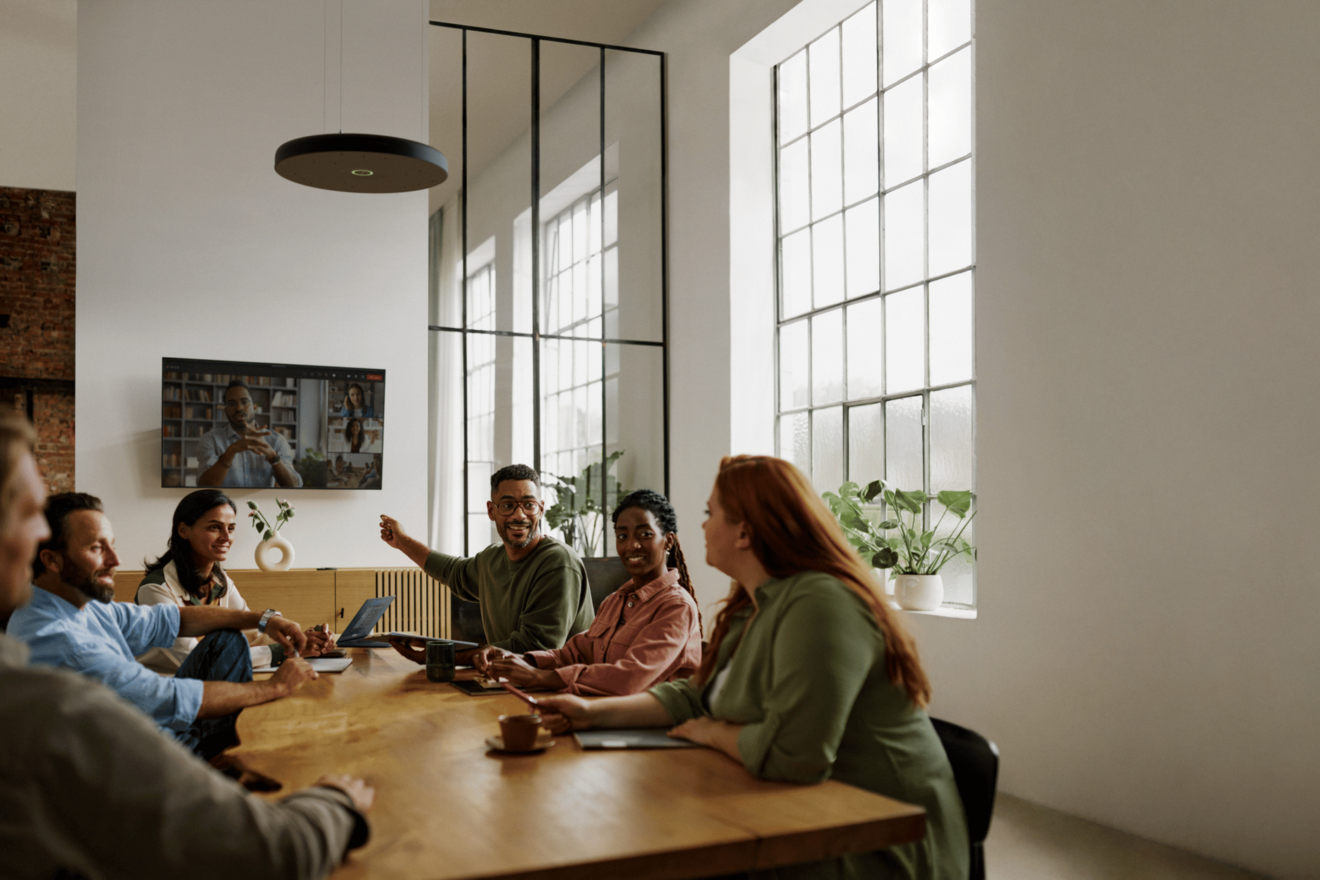 Team meeting in a modern conference room with large windows and Sennheiser TeamConnect Ceiling 2.