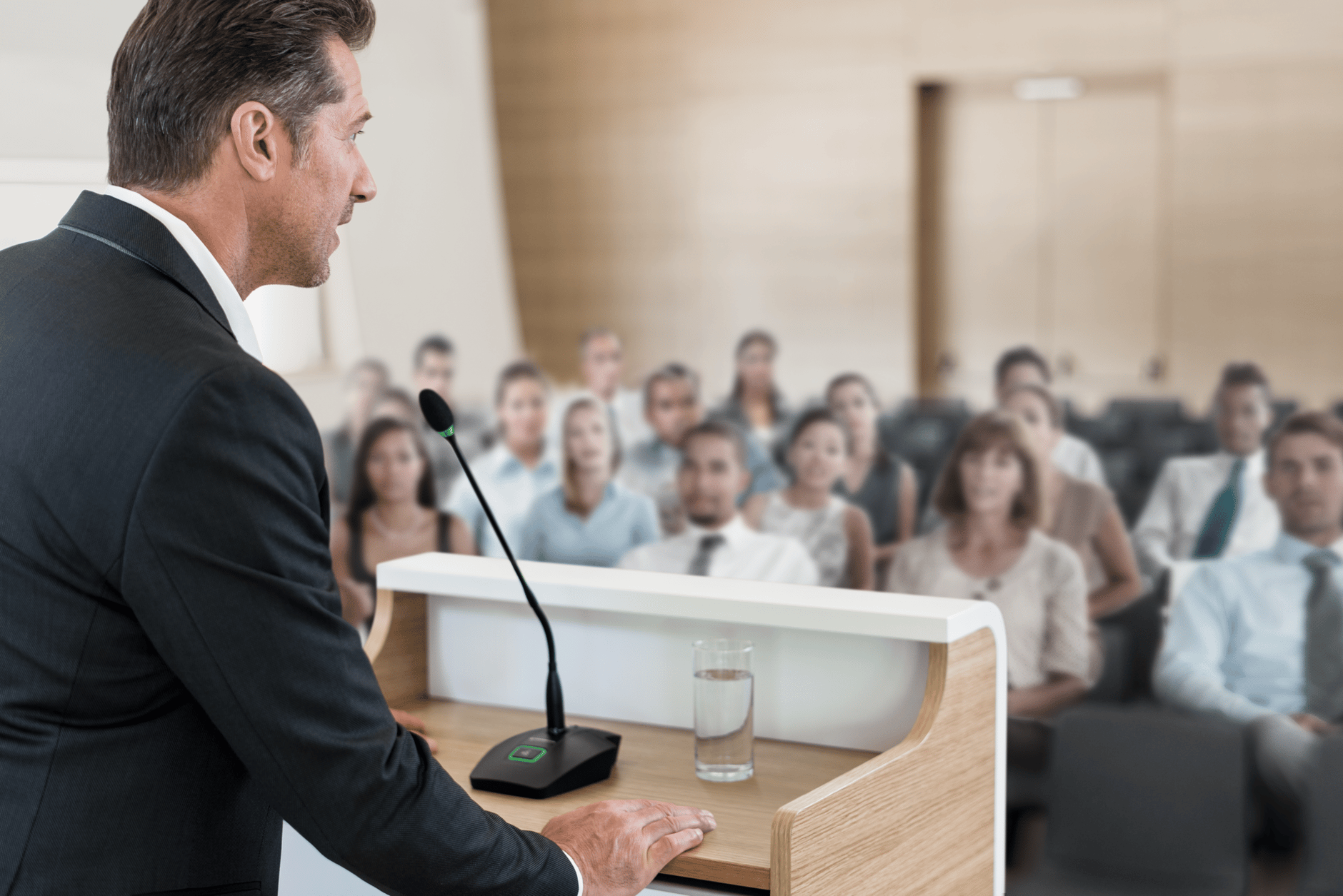 Man speaking at podium with microphone in front of audience