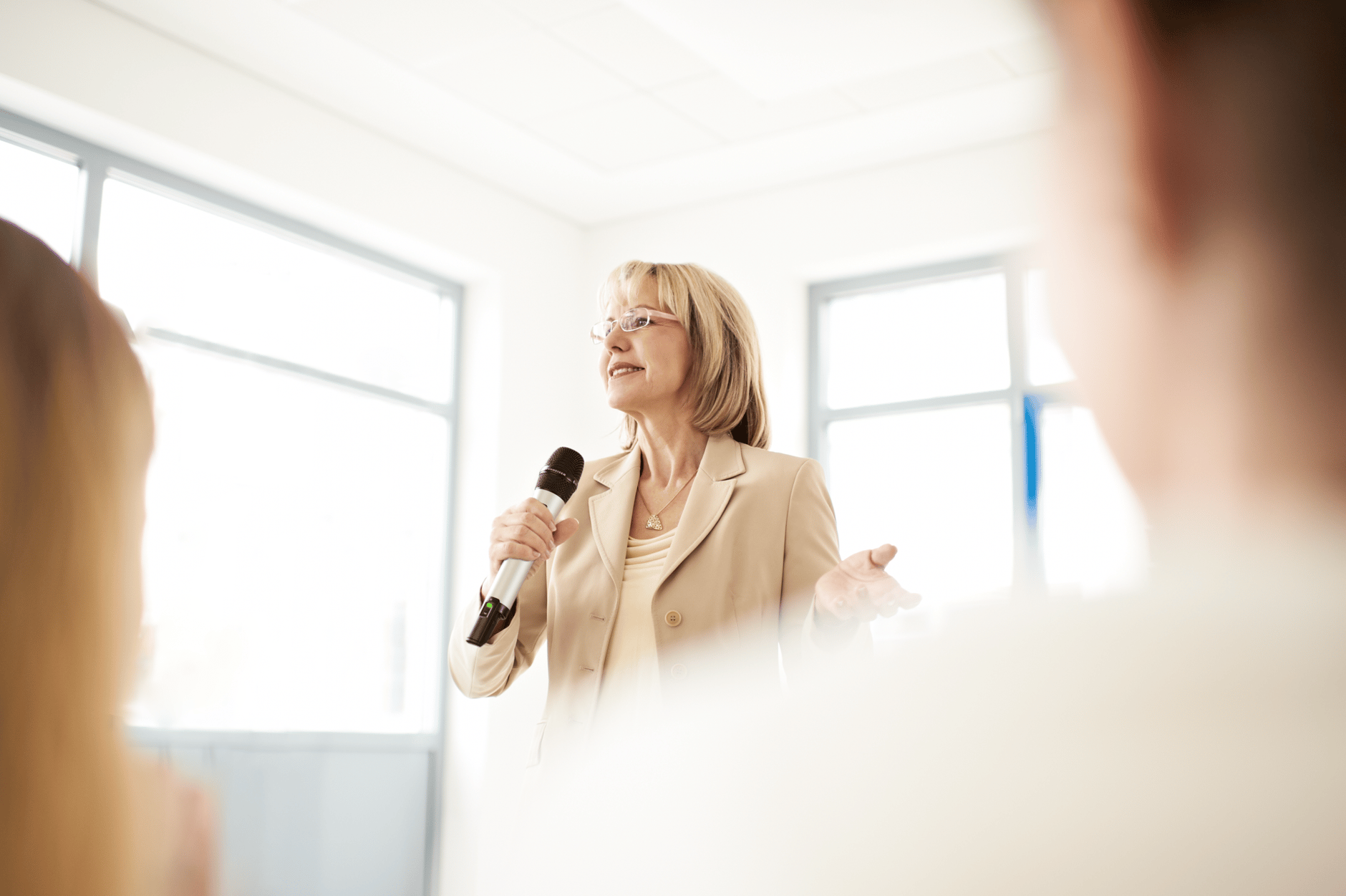 Woman giving a presentation with a microphone in a bright room.