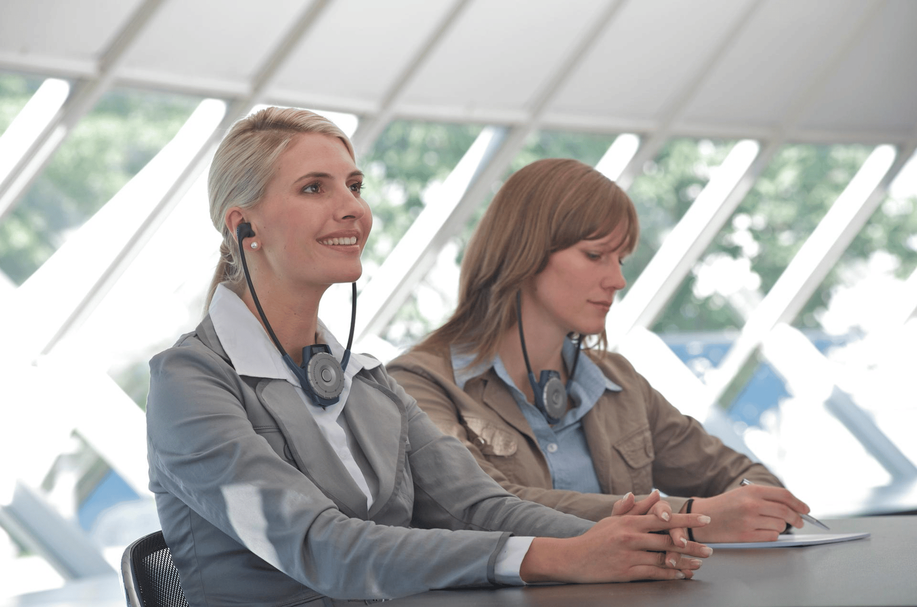 Two women wearing Sennheiser headsets in a bright, modern office setting.