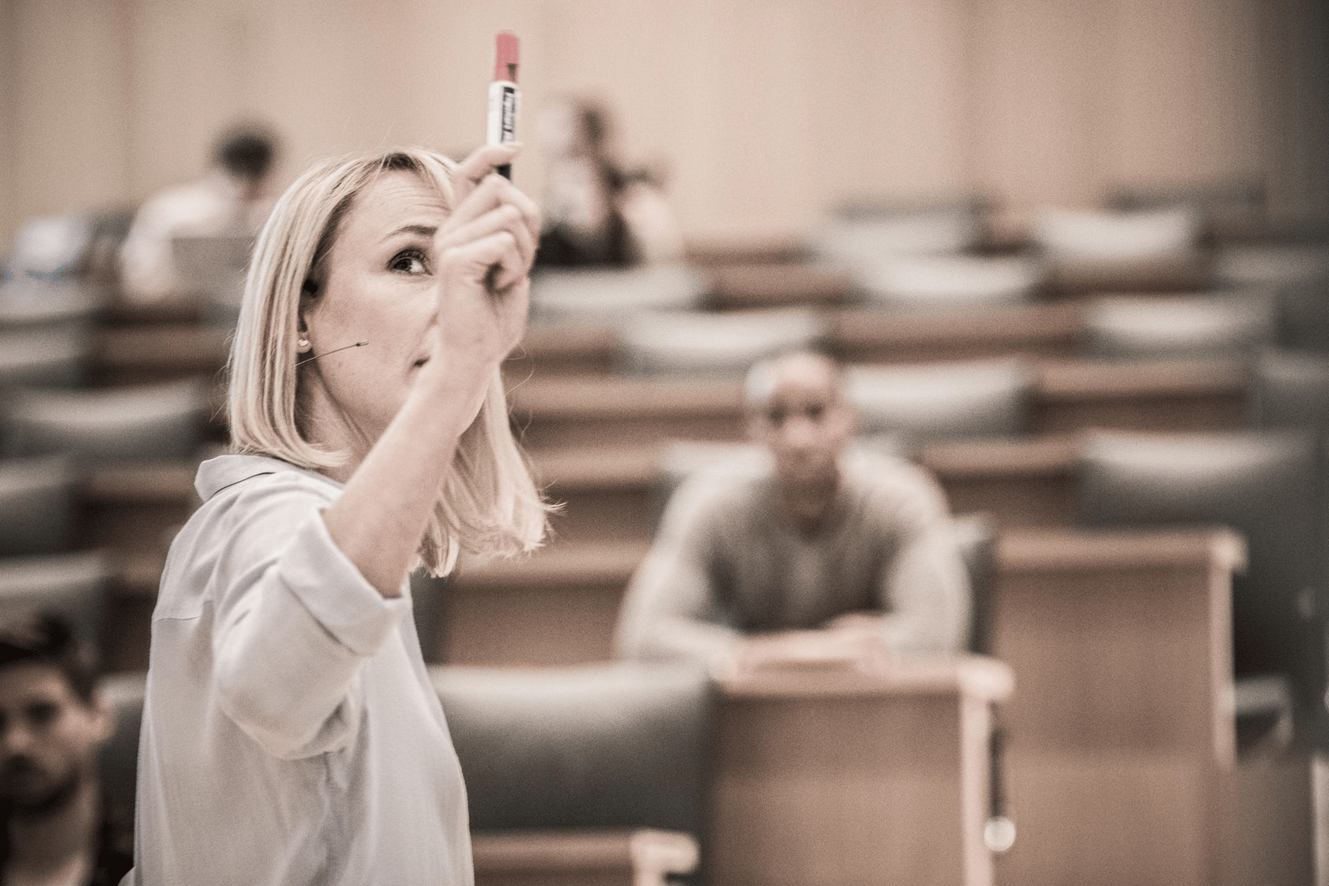 Woman holding a marker in a lecture hall.