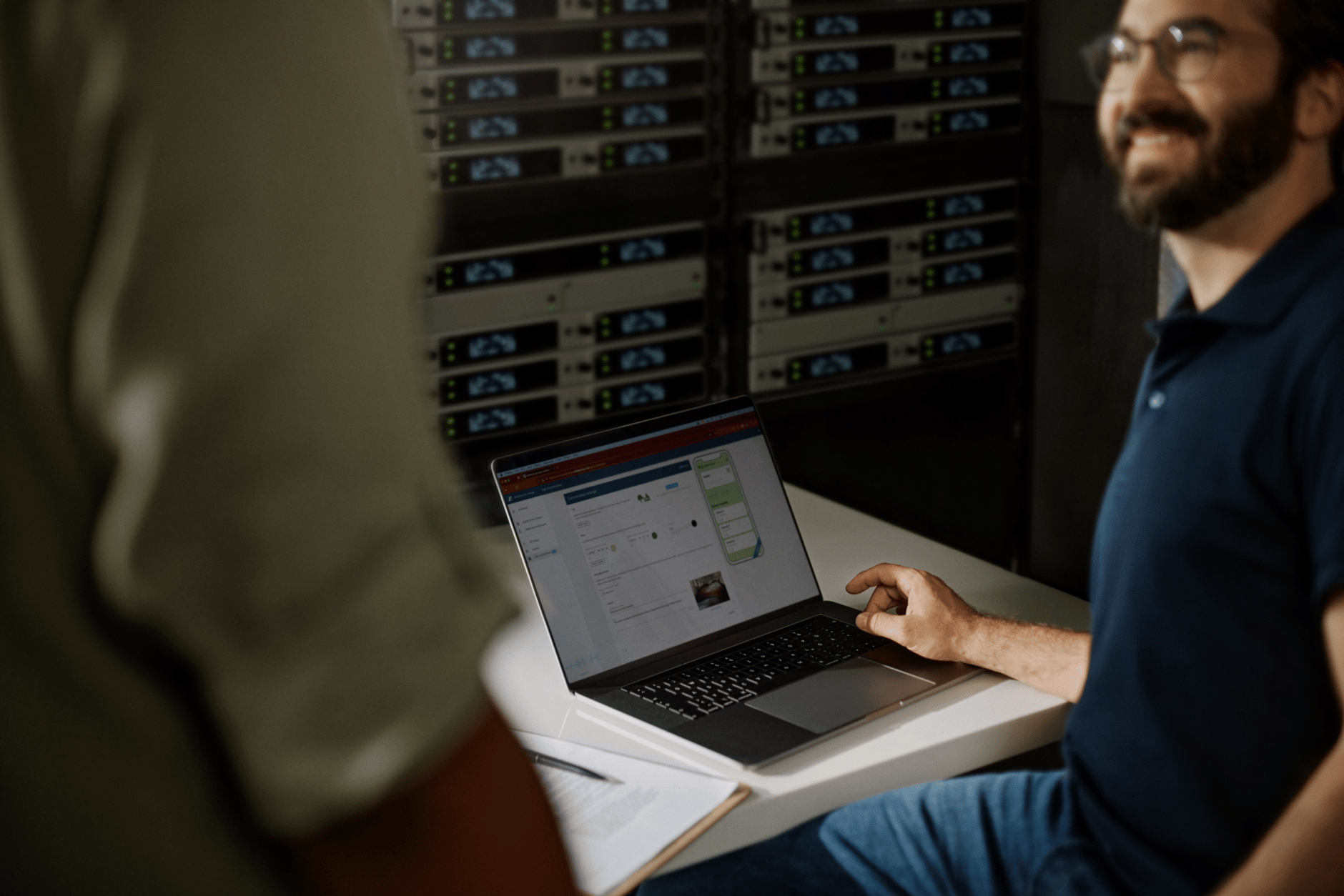 Man using a laptop in a server room.