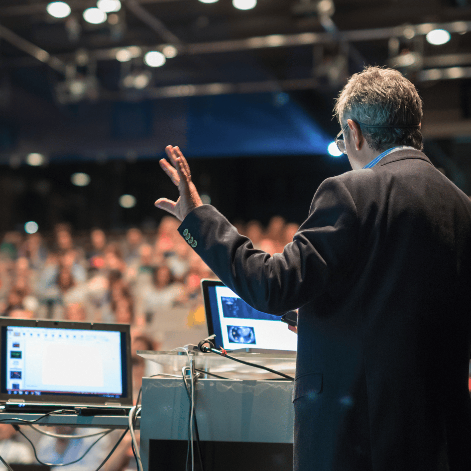 Man giving a presentation with a laptop and projector in front of an audience.