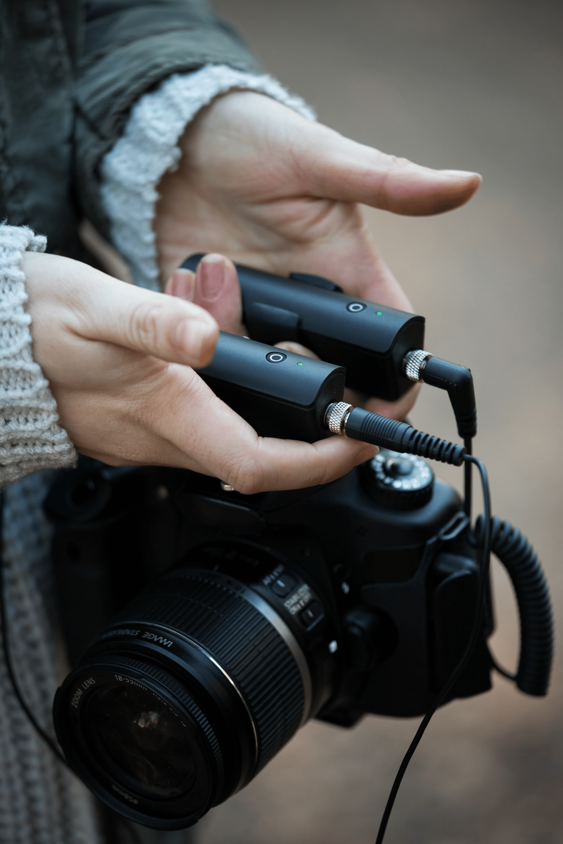 Person holding Sennheiser XS Wireless Digital audio transmitters connected to a DSLR camera.