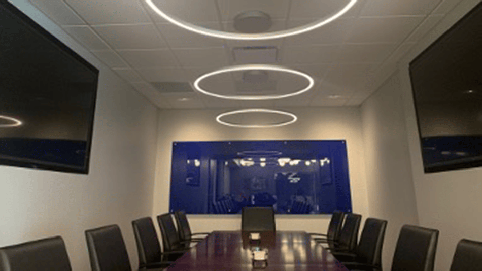 Modern conference room with circular LED ceiling lights and large screens.