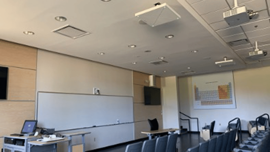 Modern classroom with projector, whiteboard, and periodic table chart on the wall.