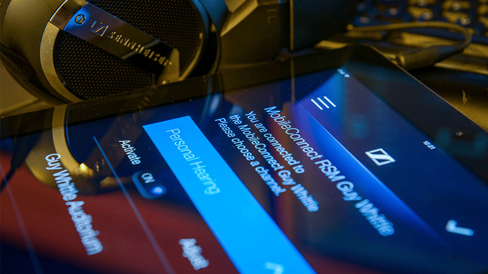 Sennheiser headphones next to a tablet displaying MobileConnect app interface.