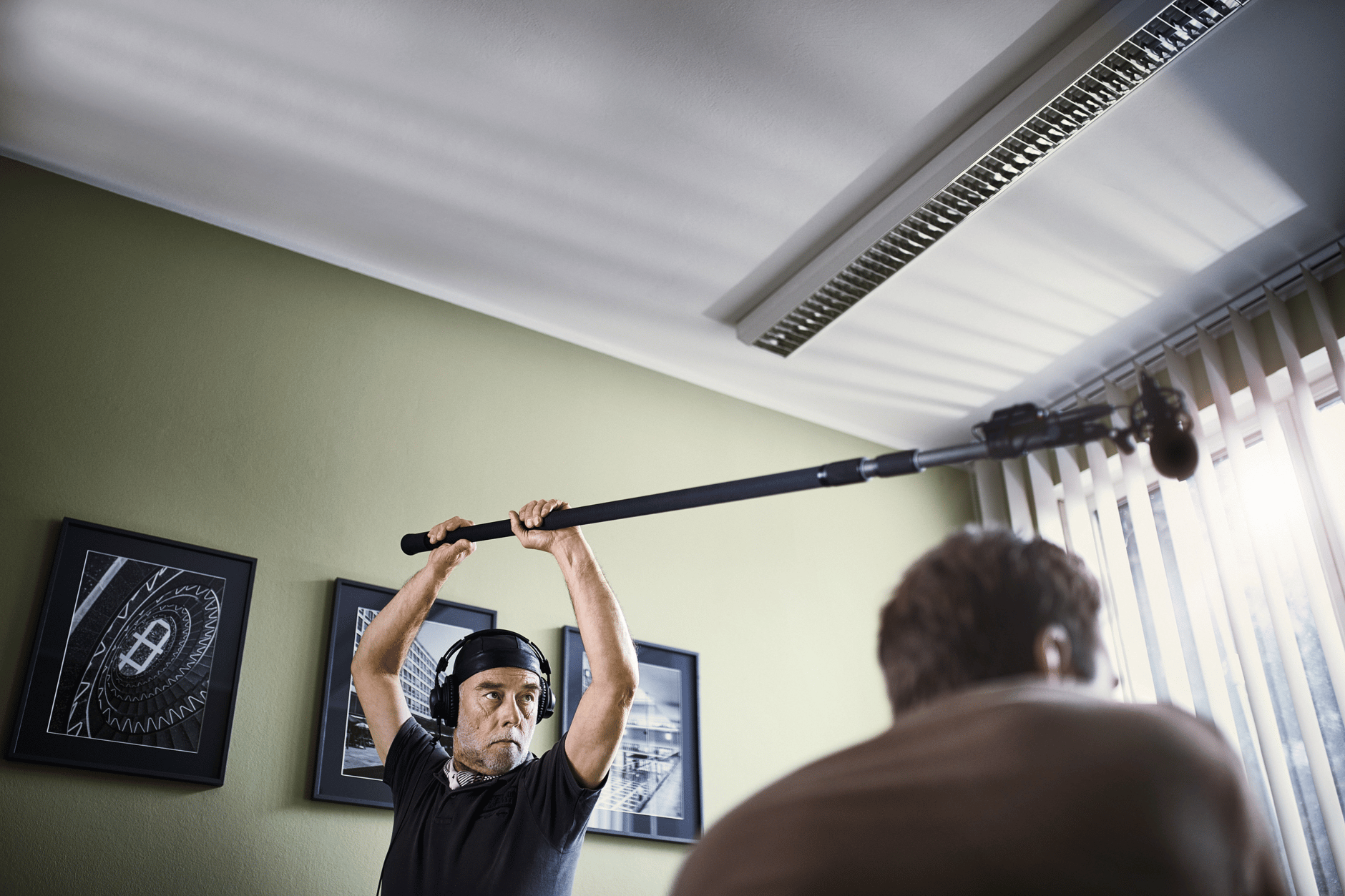 Sound engineer holding a boom microphone during a film shoot.