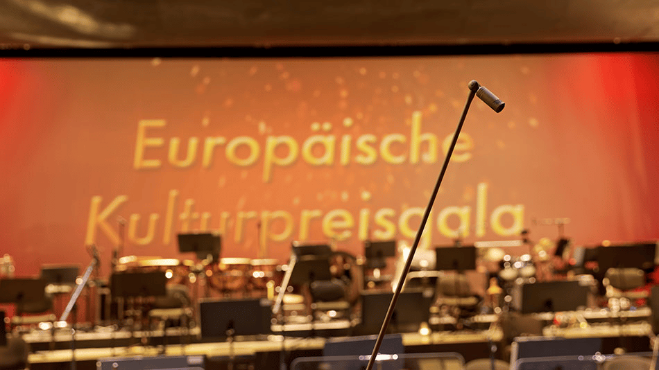 Microphone on stage with blurred European Cultural Award Gala background.