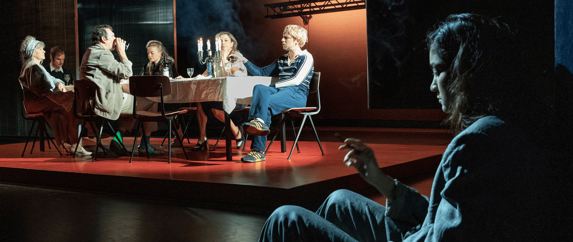Theater actors performing a dramatic scene around a dining table.