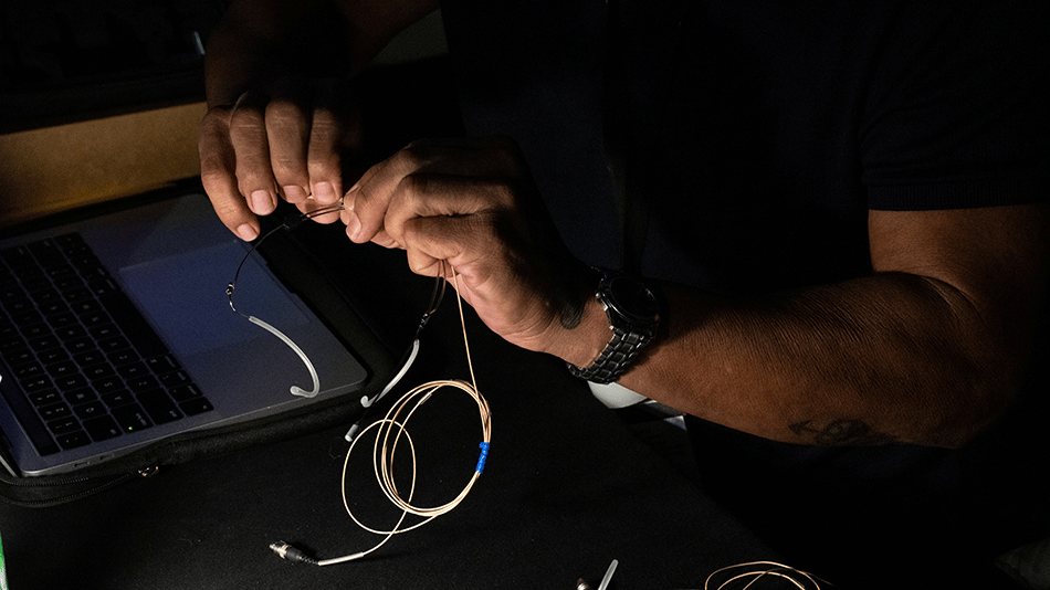 Person handling Sennheiser microphone equipment near a laptop.