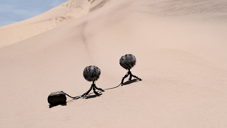 Microphones on tripods recording sound in a desert.