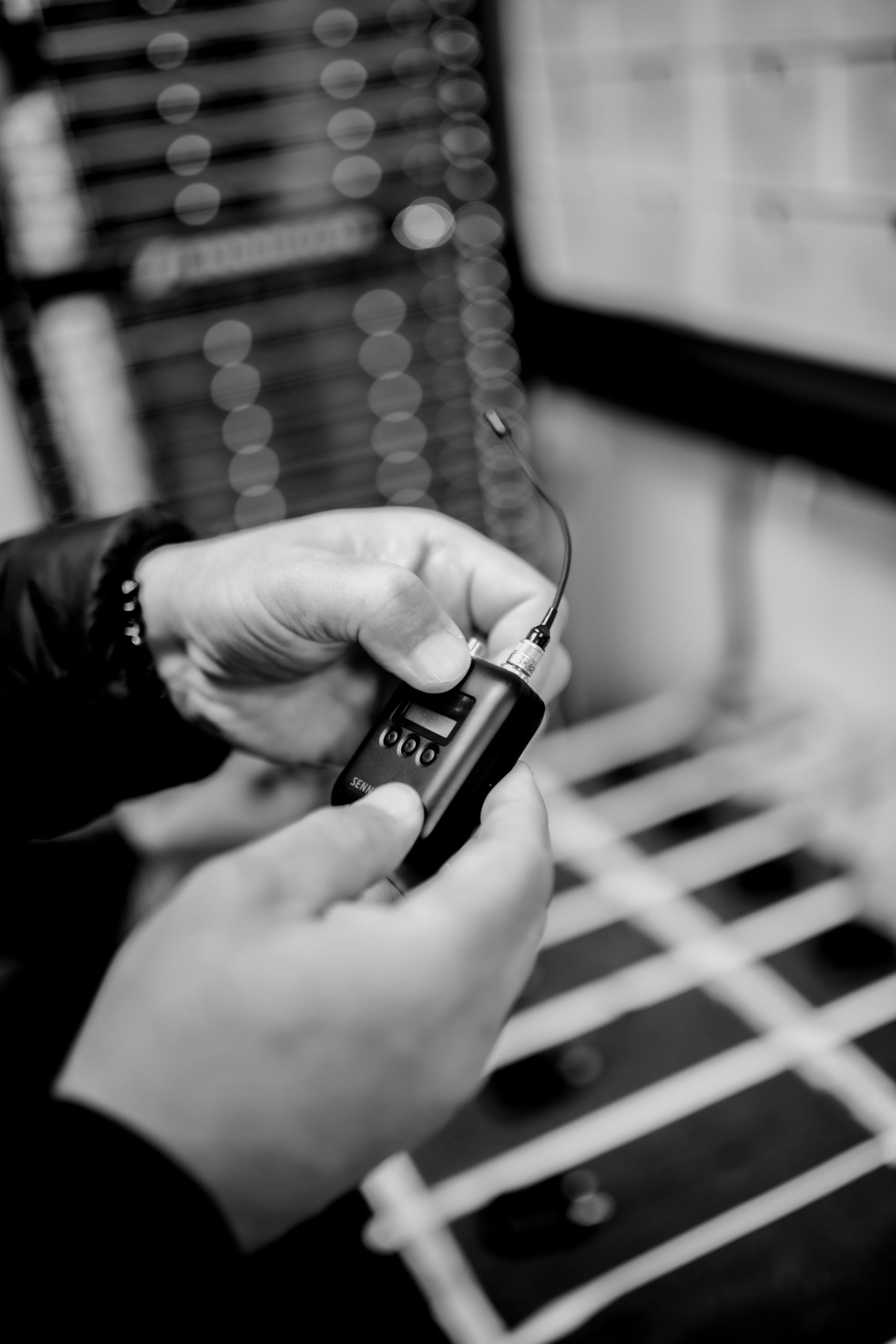 Person holding a wireless microphone transmitter in a recording studio.