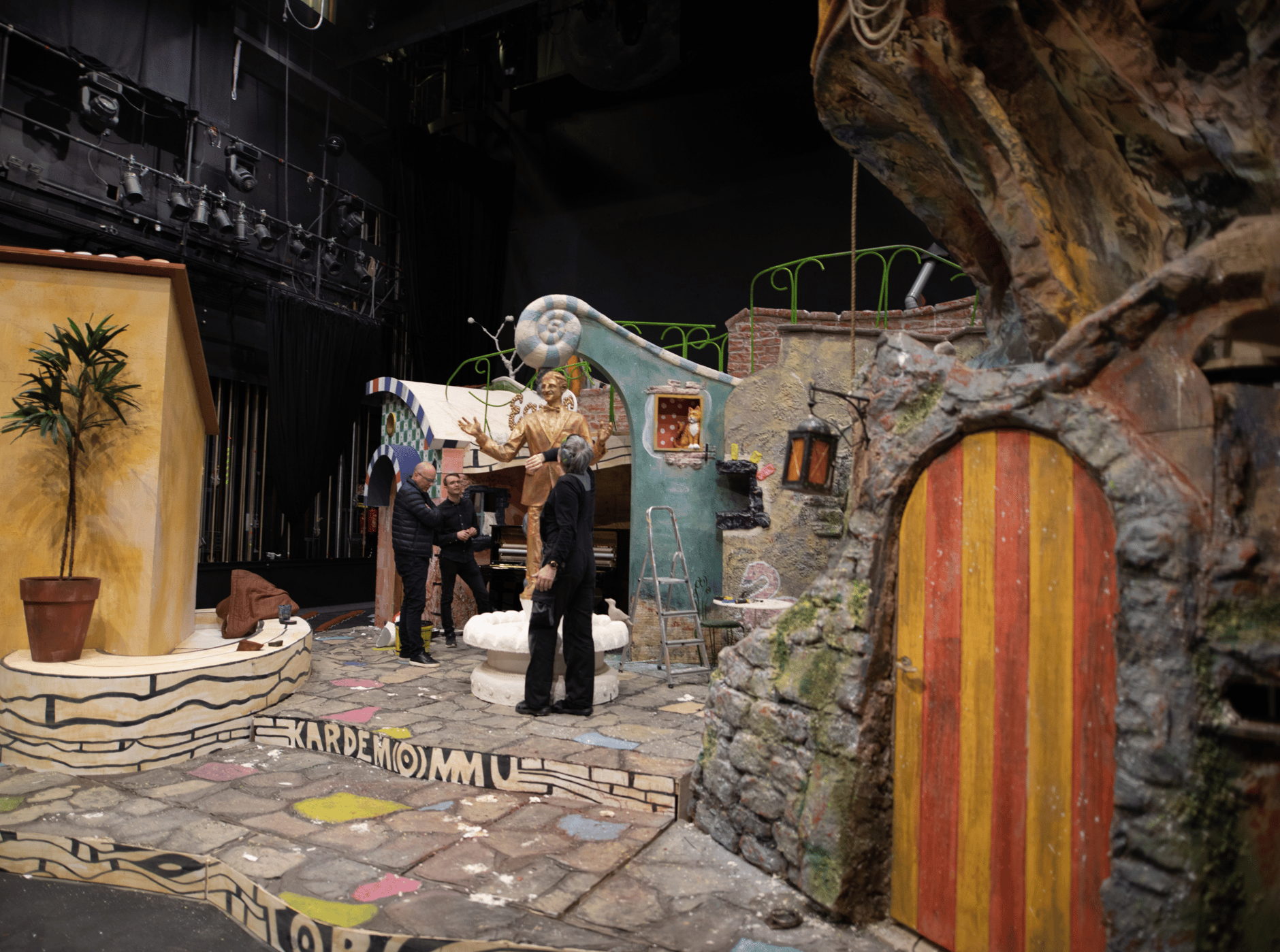 Theater stage set with colorful props and actors preparing for a performance.