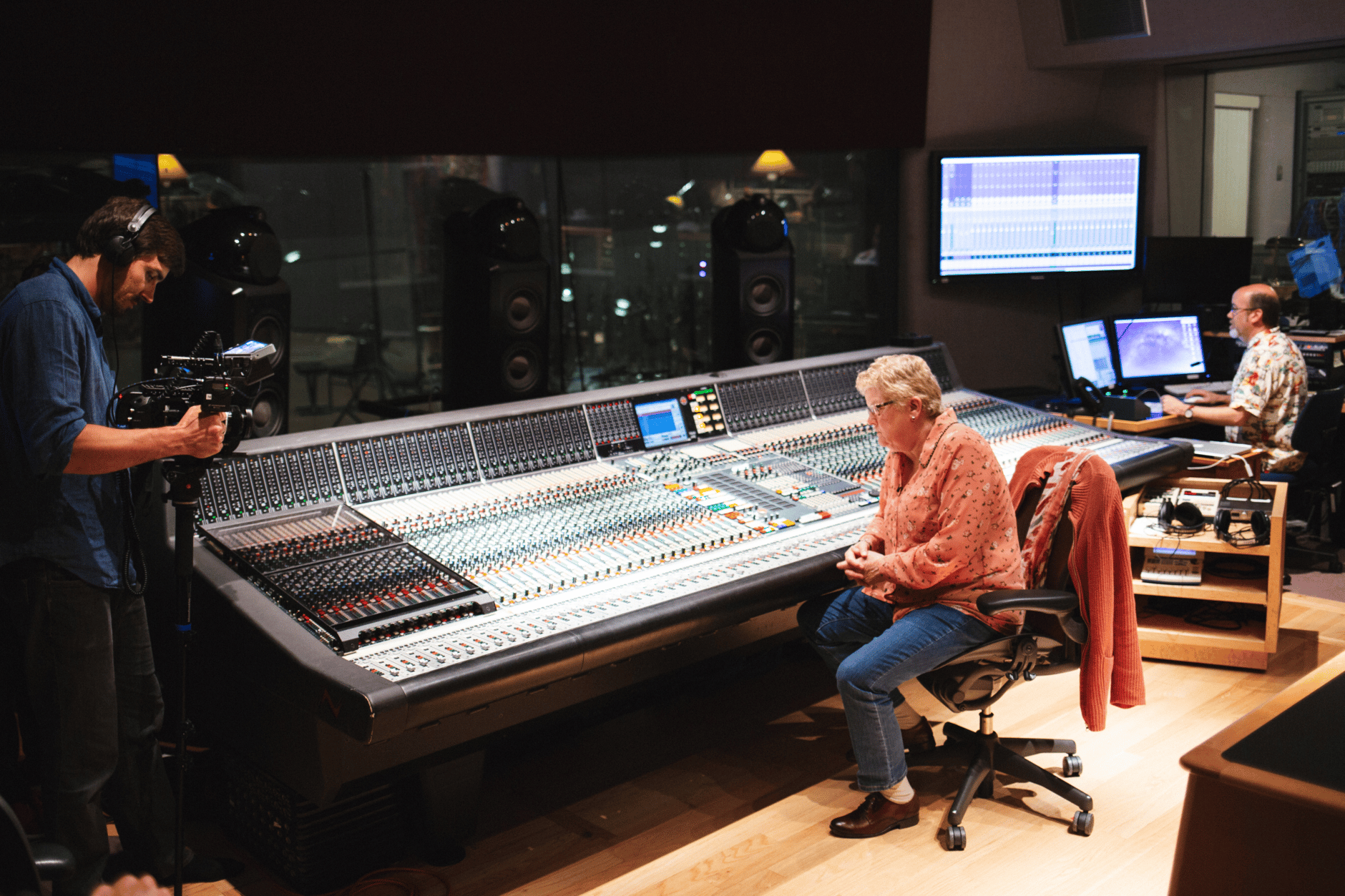 Sound engineer working at a large mixing console in a recording studio.