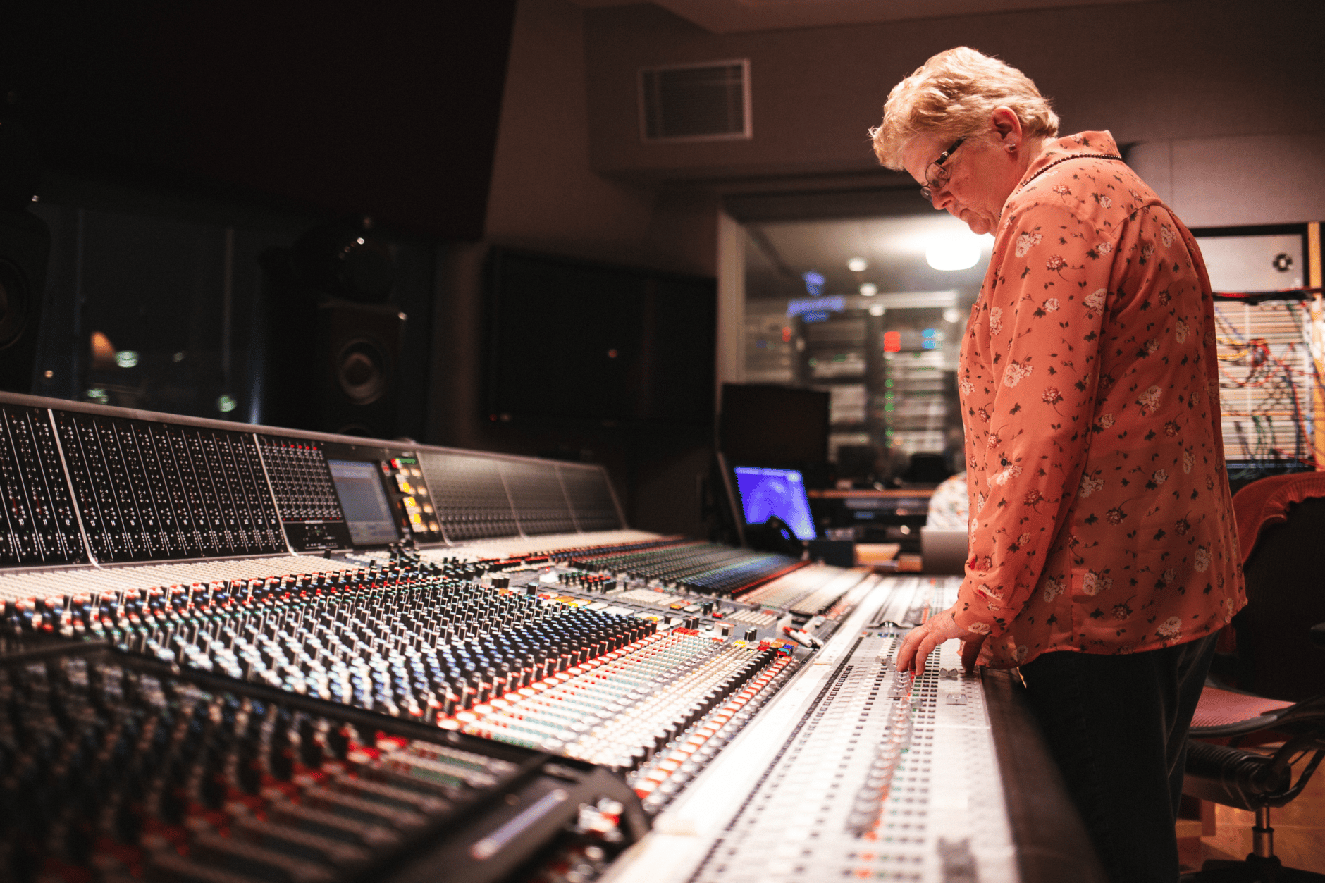 Person operating a large audio mixing console in a recording studio.