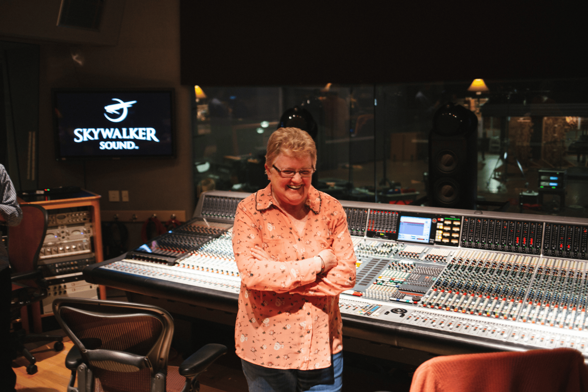 Person standing in front of a large audio mixing console at Skywalker Sound studio.