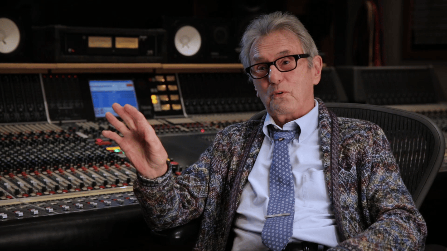 Man in a recording studio with audio mixing console.
