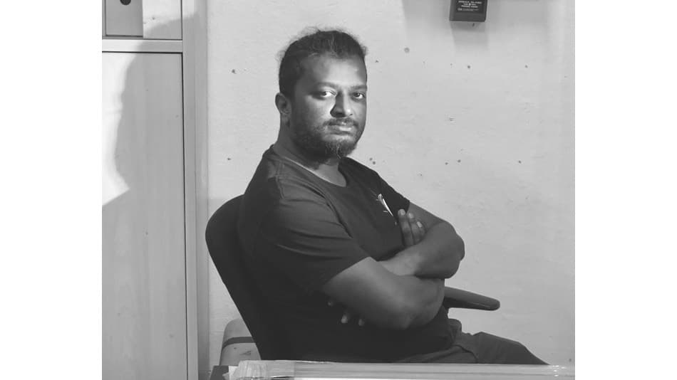 Man sitting on a chair with arms crossed in a black and white photo.
