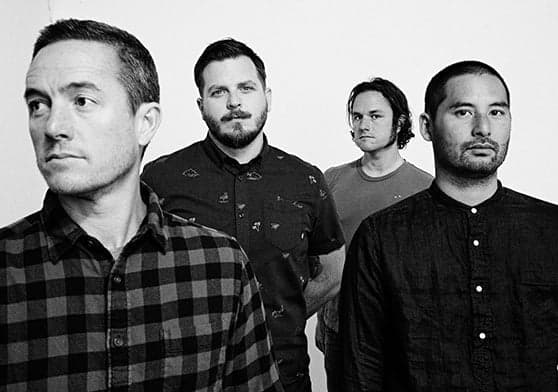Four men standing together in black and white photo.