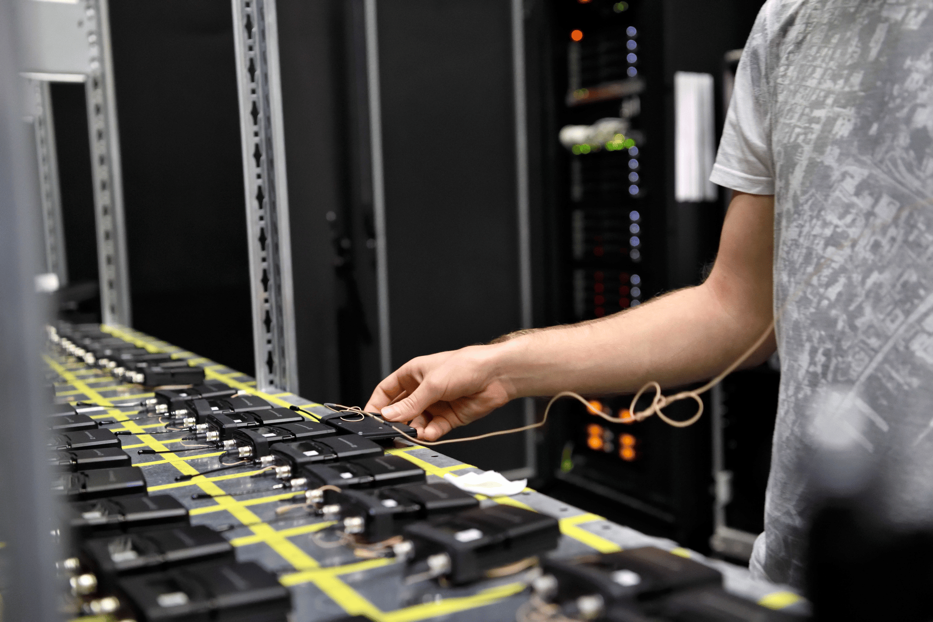 Person adjusting wireless microphone transmitters in a professional audio setup.