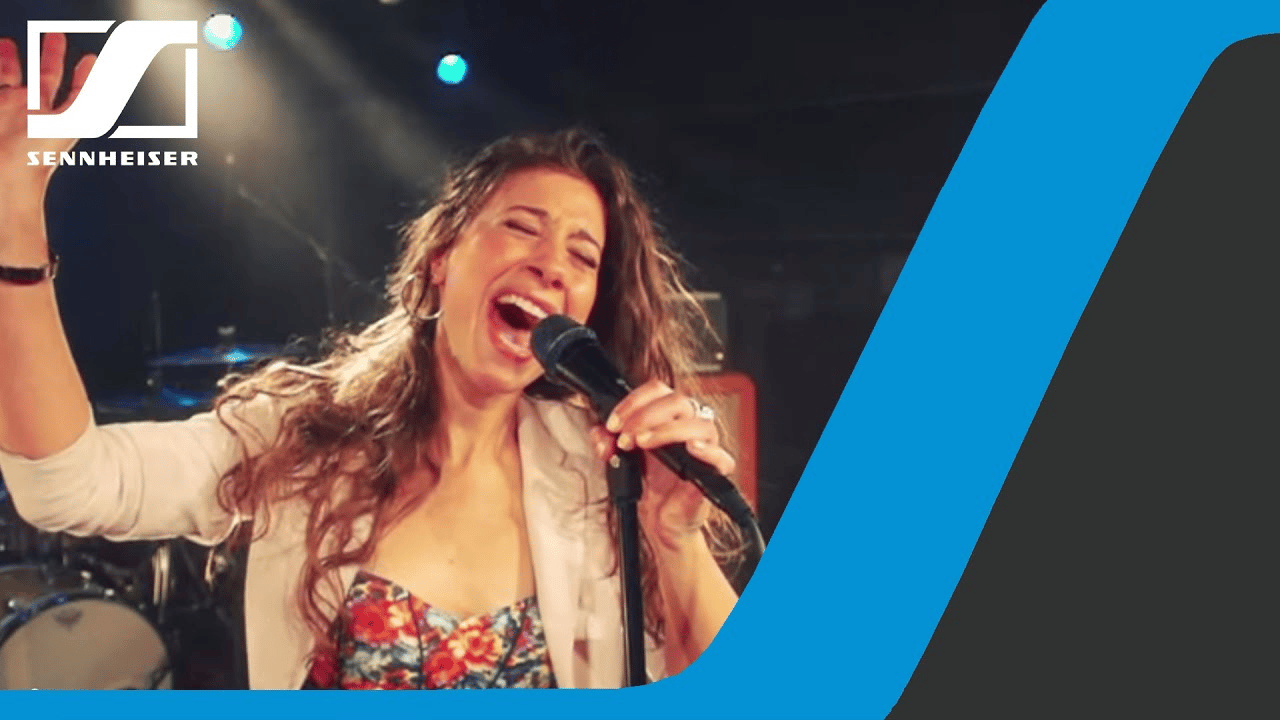 Woman singing passionately into a Sennheiser e 935 microphone on stage.