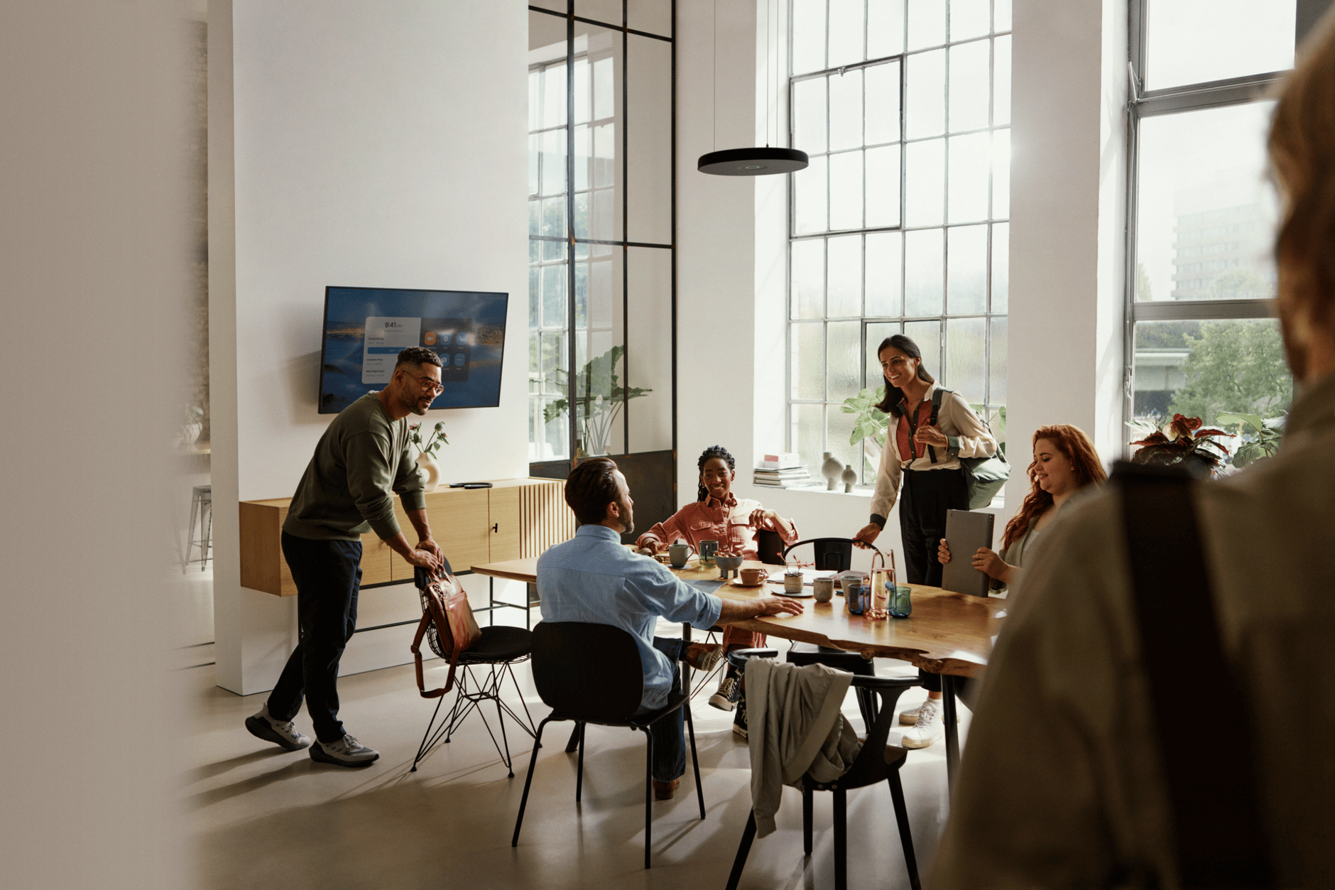People collaborating in a modern office with large windows and natural light.