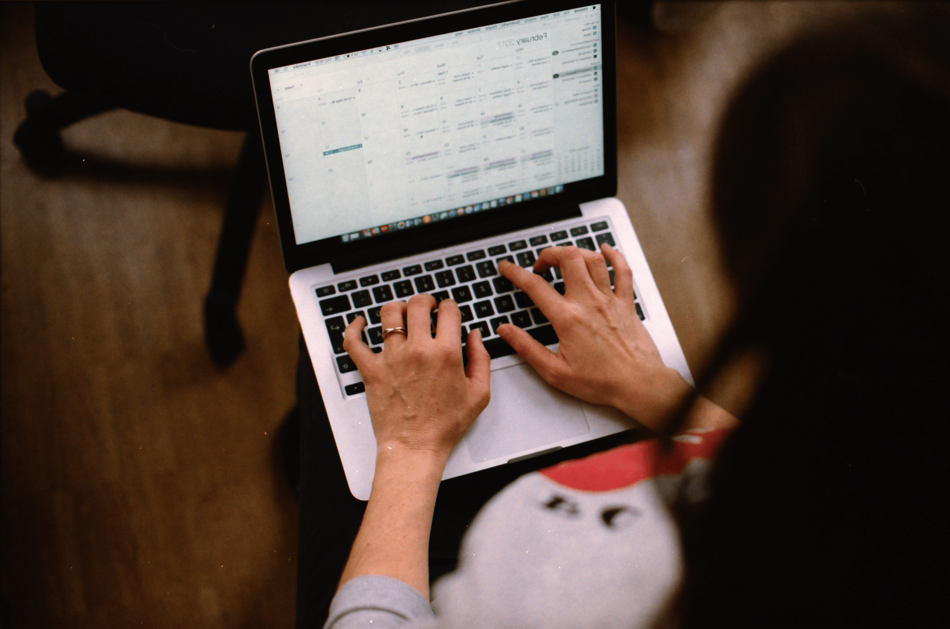 Person typing on a laptop with a calendar on the screen