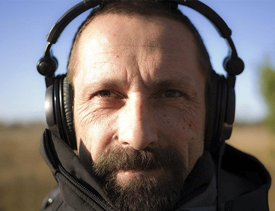 Man wearing headphones outdoors with a serious expression.