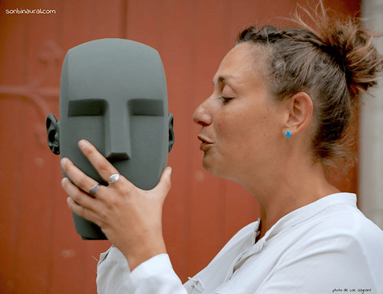 Woman interacting with a KU100 binaural microphone mannequin head.