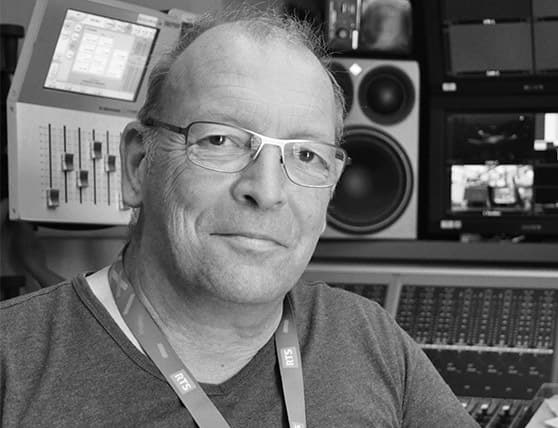 Man in recording studio with audio equipment and mixing console.