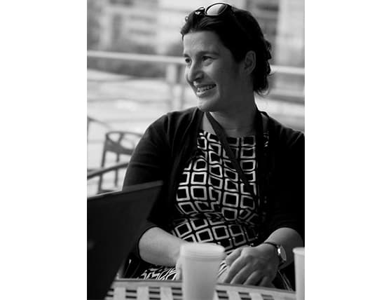 Woman smiling while sitting at an outdoor café table.