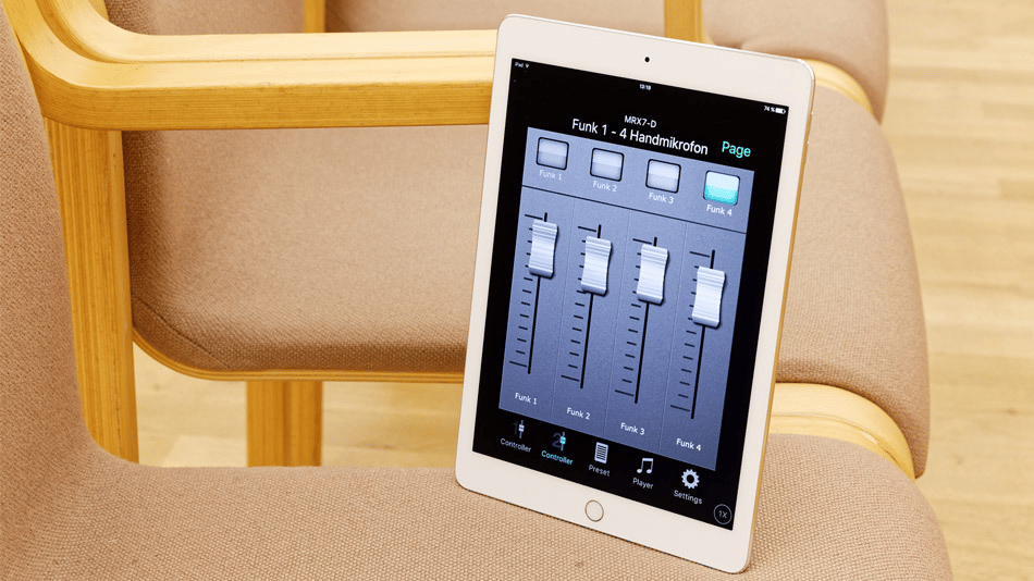 Tablet displaying audio control interface resting on a wooden chair.