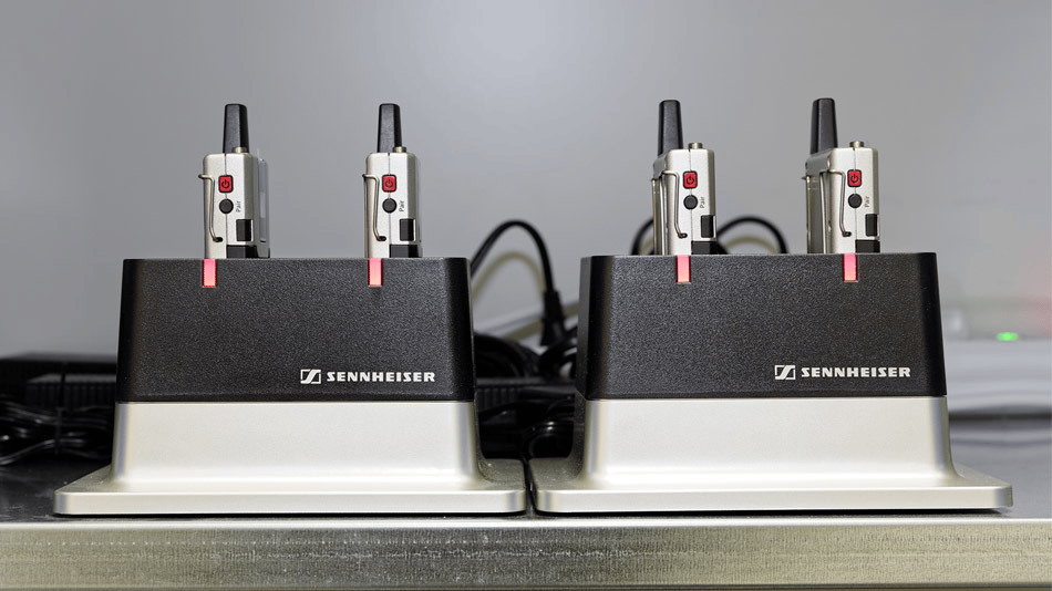 Sennheiser wireless microphone charging stations on a metal surface.
