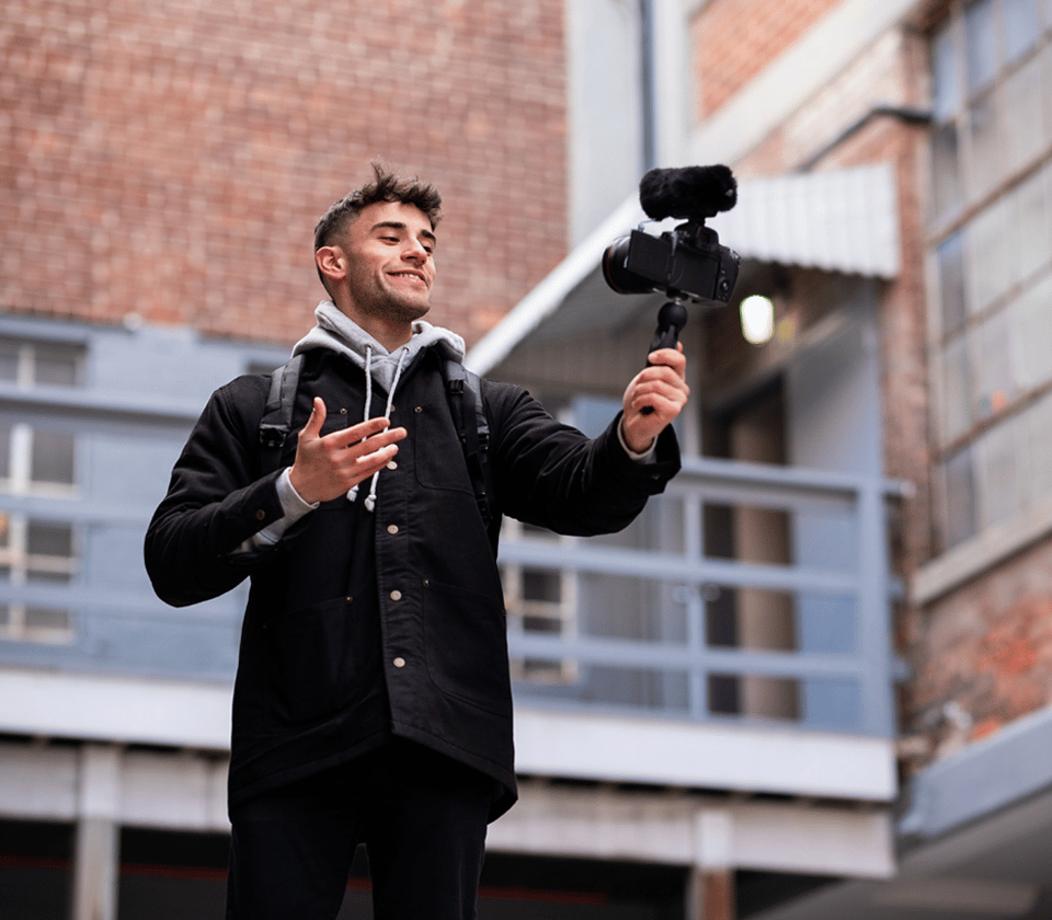 Man using Sennheiser MKE 400 microphone on a camera for vlogging outdoors.