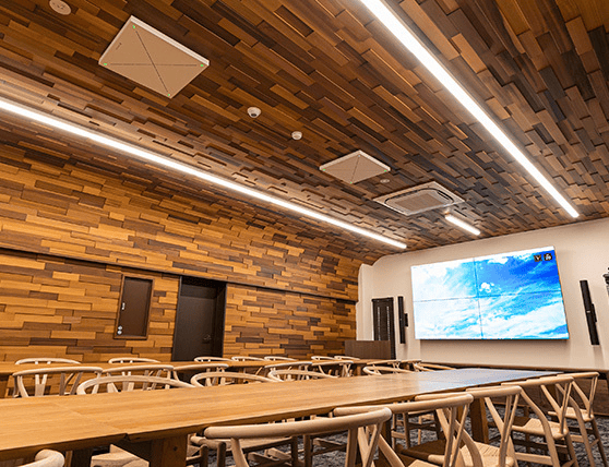 Modern conference room with wooden walls and ceiling, large screen display, and stylish chairs.