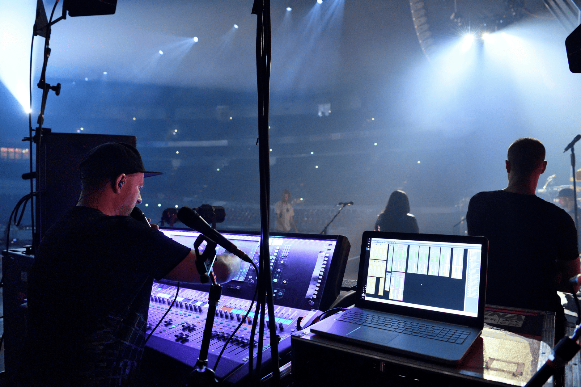 Sound engineer operating audio equipment on stage during a live concert.