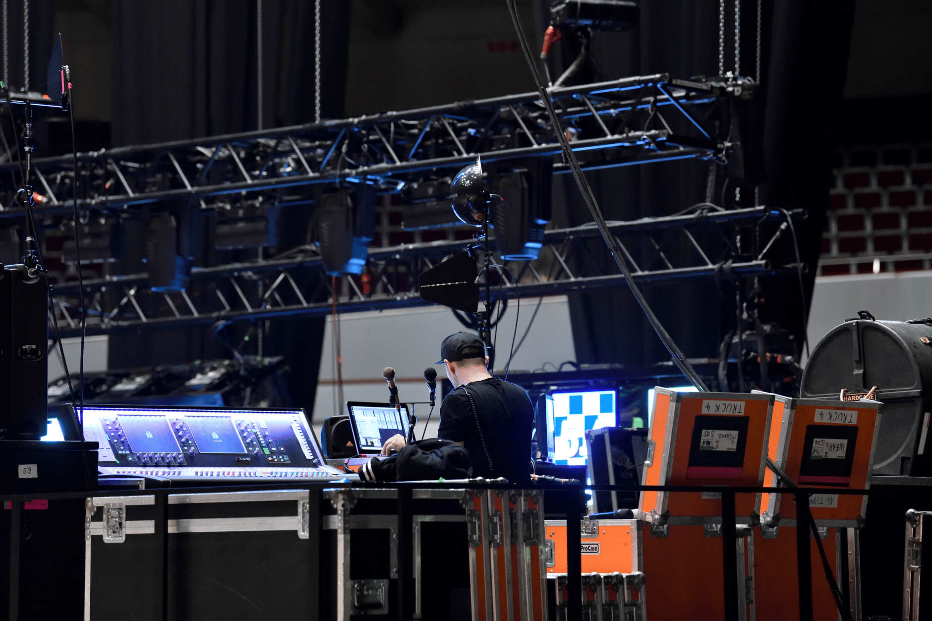 Sound engineer working at a live concert stage setup with audio equipment and lighting rig.