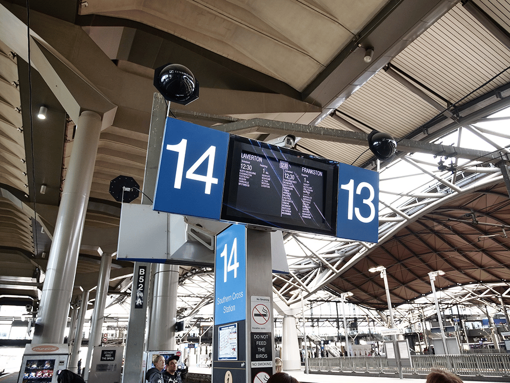 Train station platform with digital display showing departure times at Southern Cross Station.