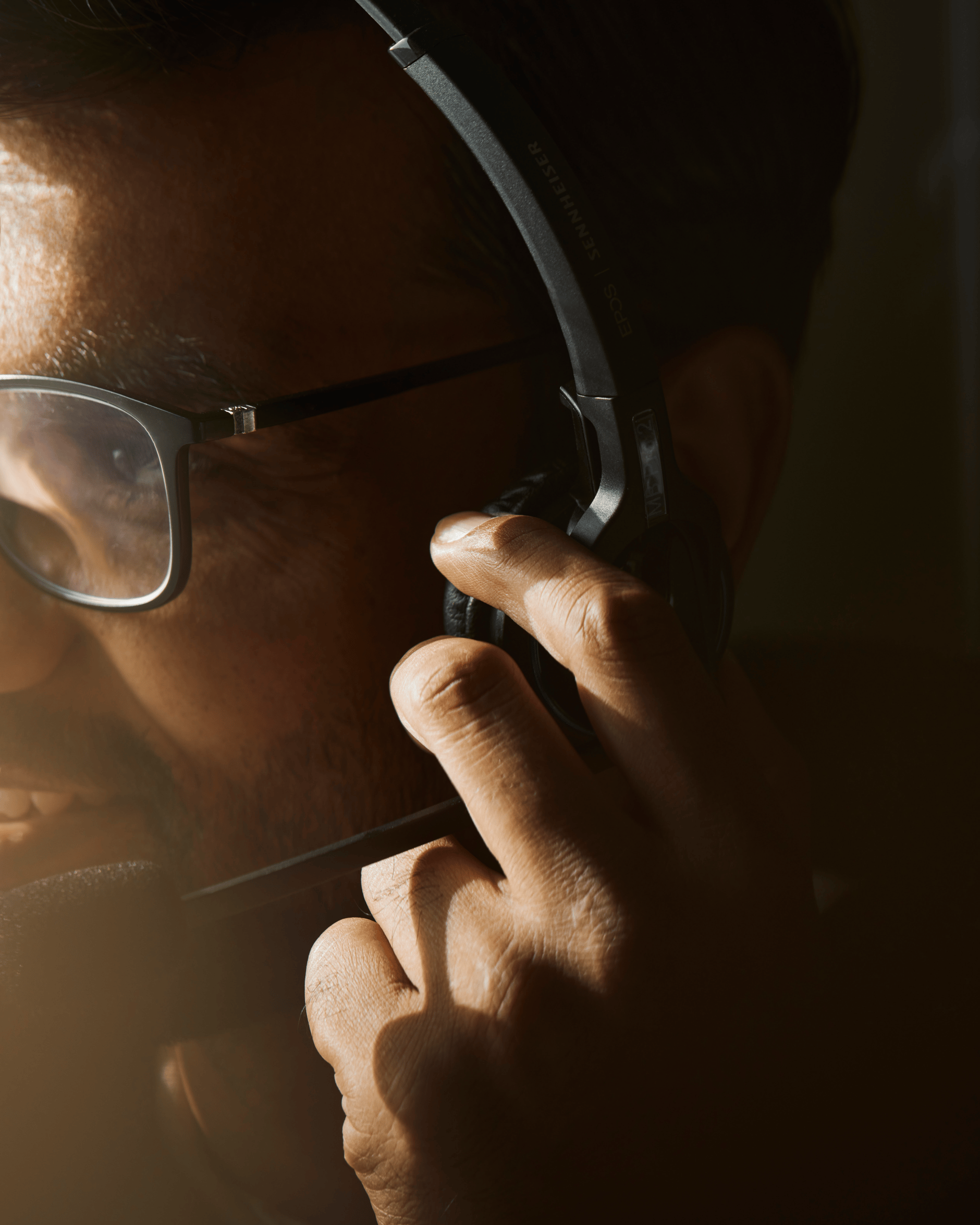 Man wearing glasses using a Sennheiser headset with microphone.